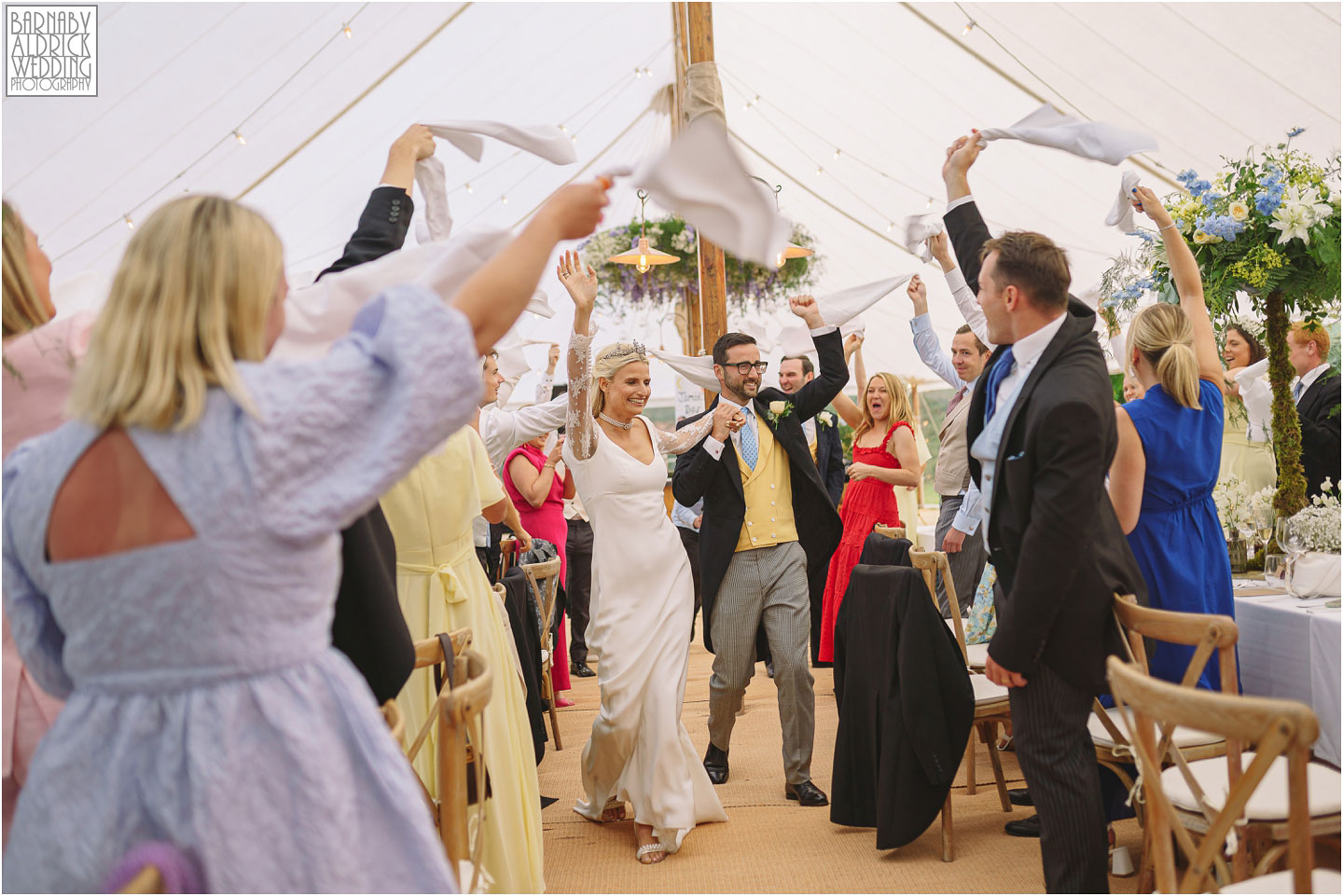 Candid photos of the entrance of the bride and groom at a wills marquee wedding by Yorkshire Wedding Photographer Barnaby Aldrick