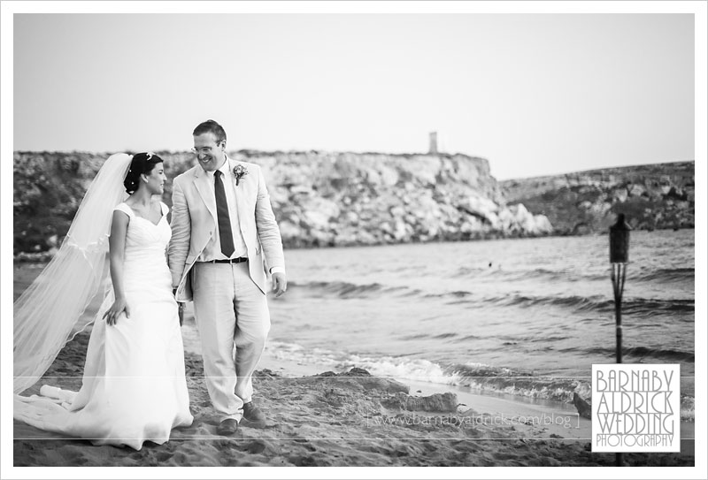 Relaxed portraits of a couple walking along a beach at their destination wedding in Malta