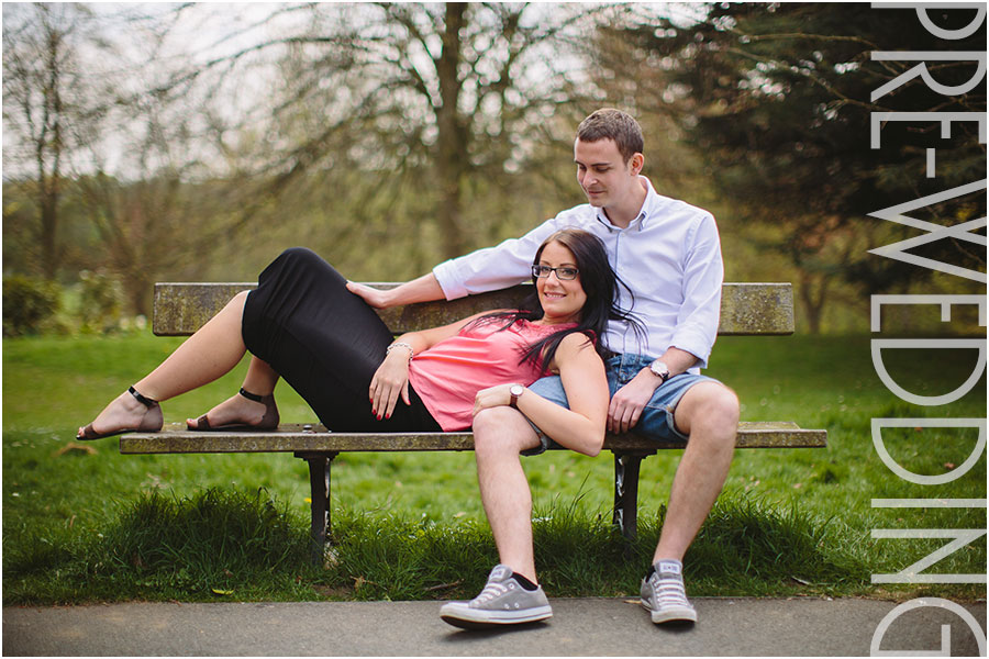 A couple pose on a bench in Roundhay Park for relaxed practice portraits at their pre-wedding shoot at The Mansion in Leeds