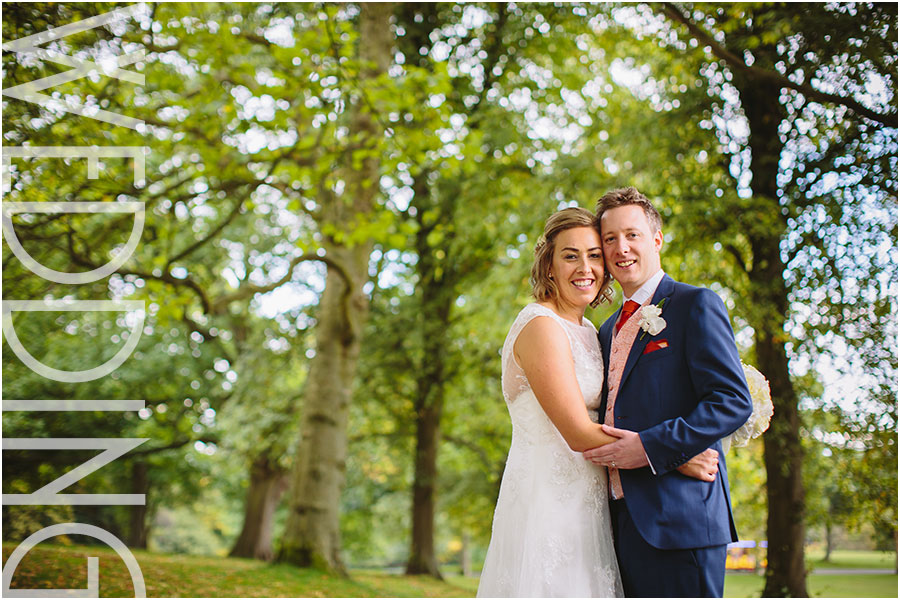 A bride and groom pose for relaxed wedding photos in Roundhay Park's tree lined avenues by The Mansion in Leeds in Yorkshire