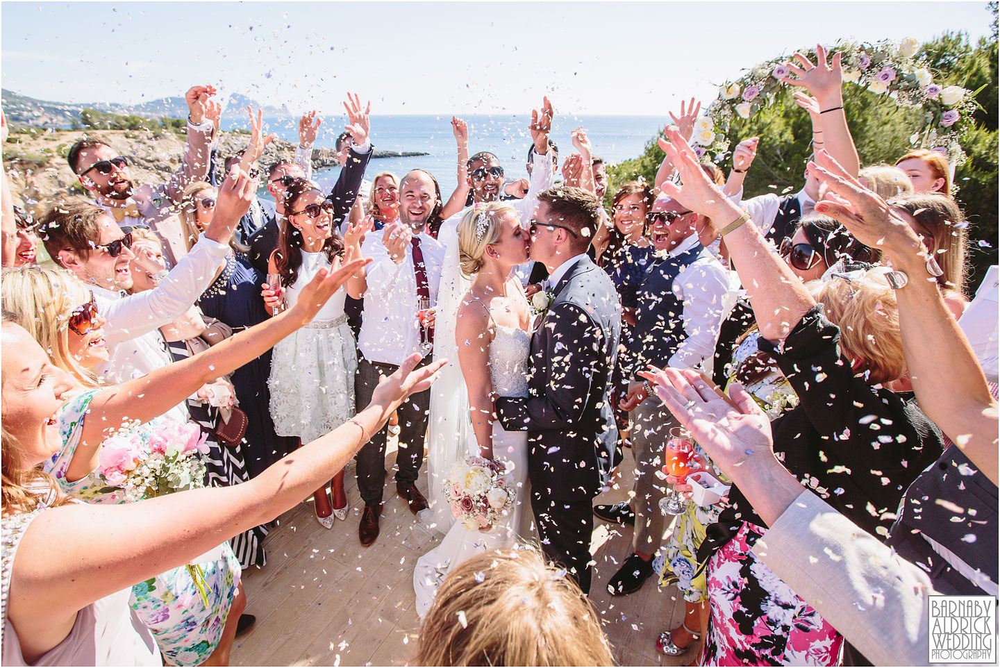A couple kiss under a dramatic confetti toss at their destination wedding at Elixir Shore Club in Ibiza