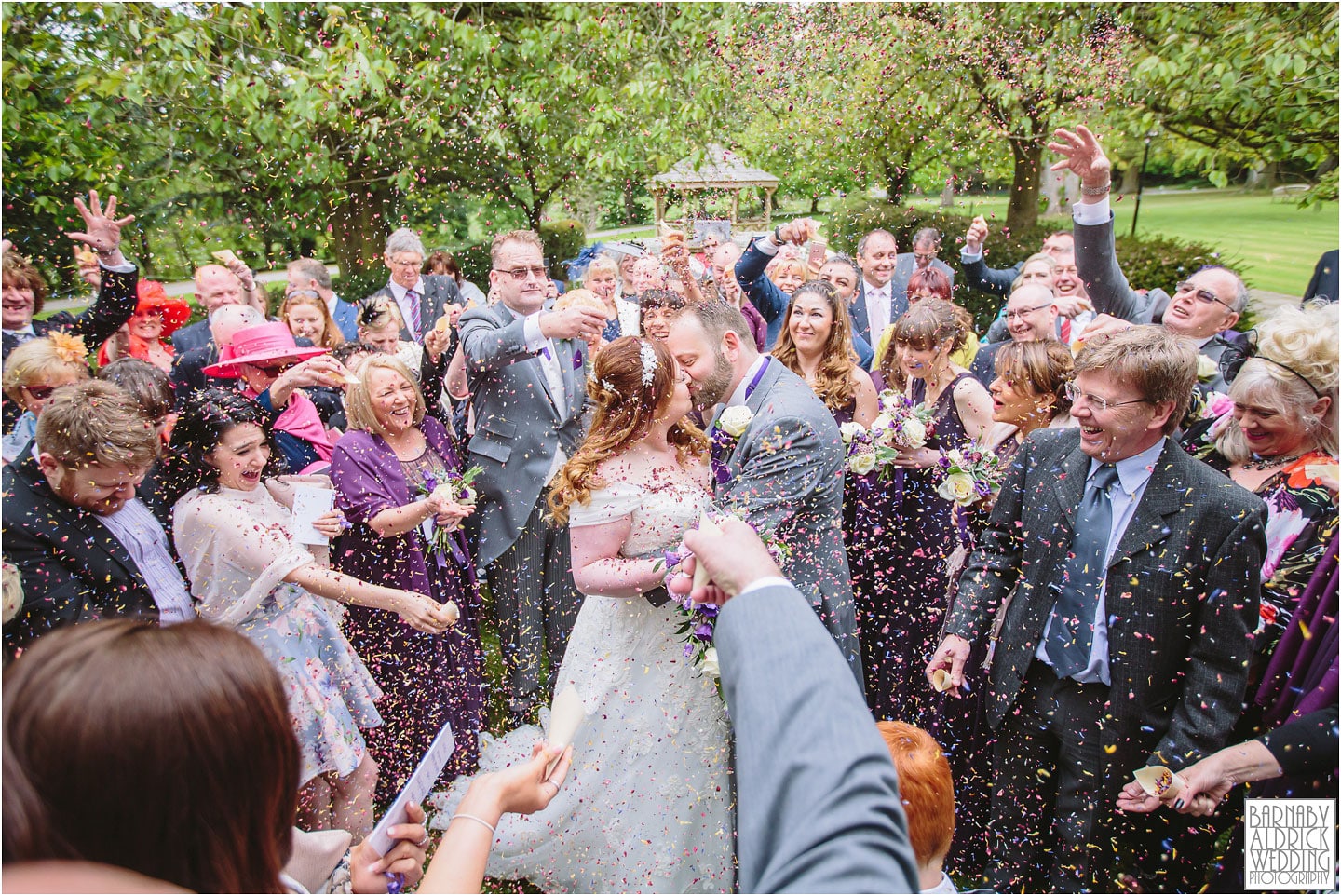 A bride and groom kiss in a sea of colourful confetti at Hazlewood Castle, Yorkshire's best ancient castle wedding venue