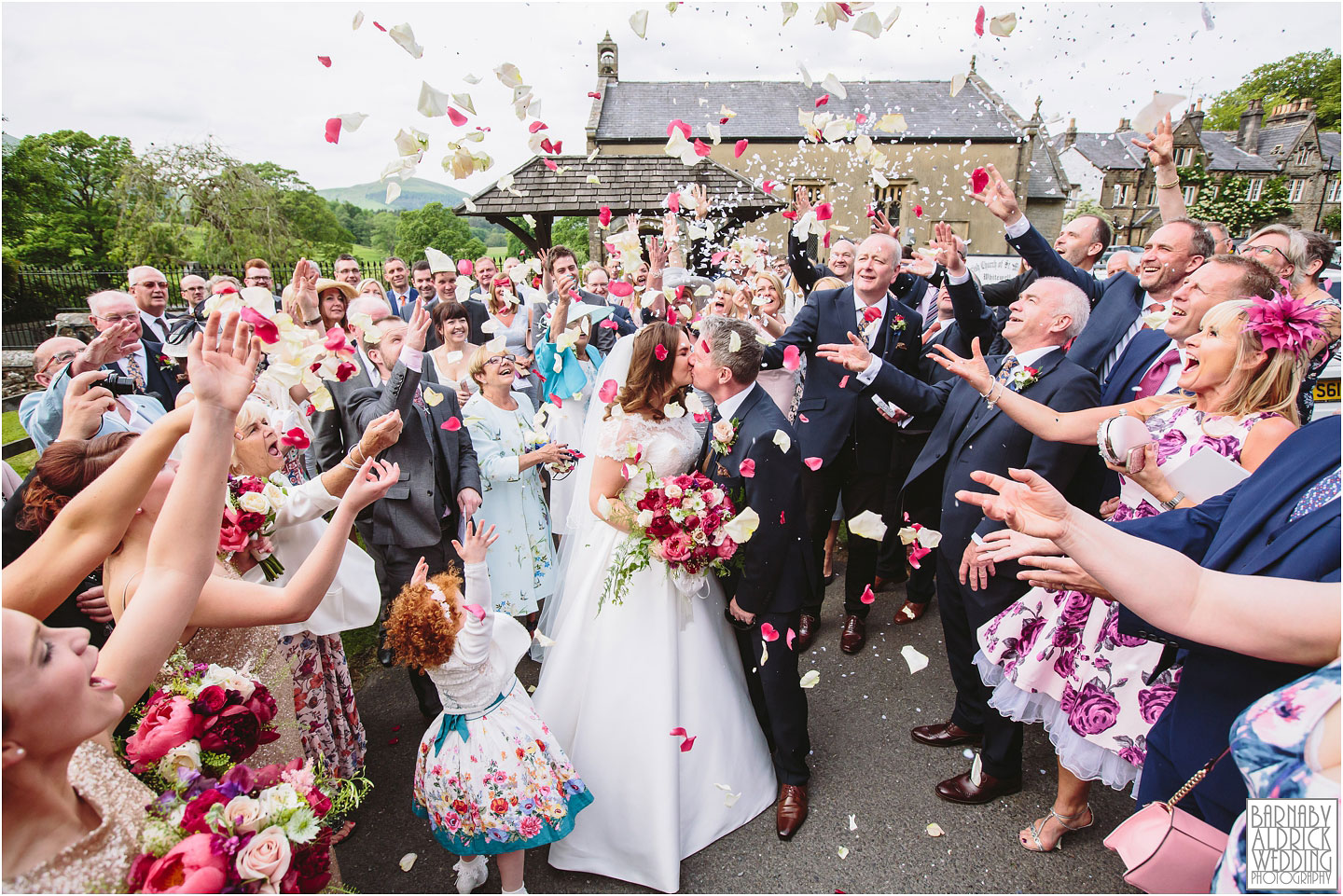 A bride and groom kiss under colourful confetti at their wedding at The Inn at Whitewell in Lancashire