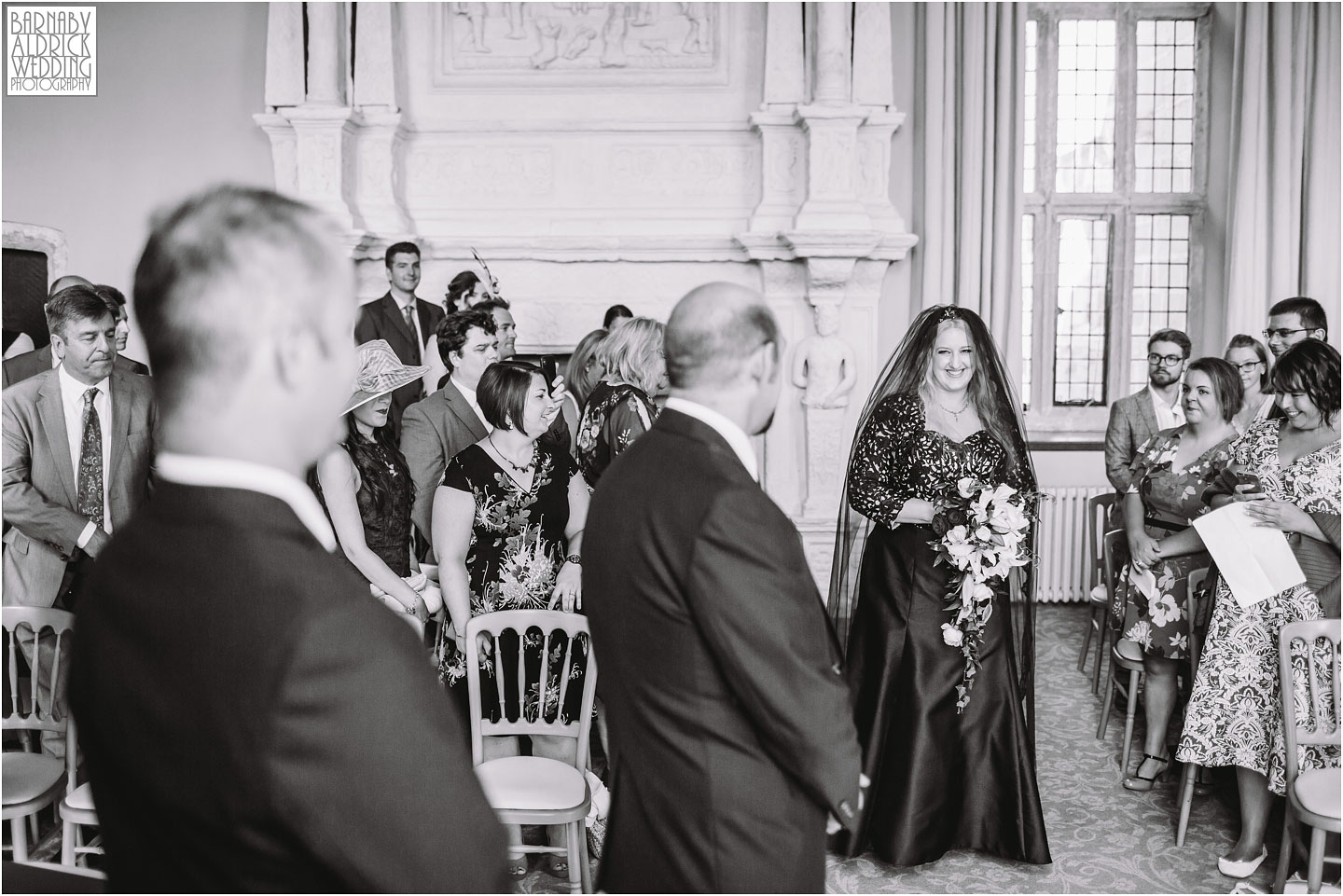 A wedding ceremony photograph at Fountains Abbey of the bride walking down the ailse