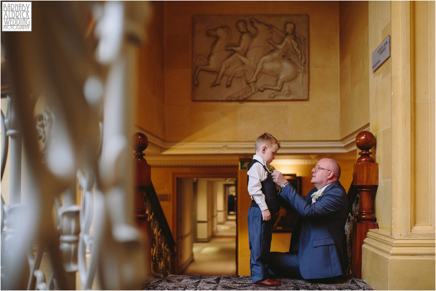 A wedding photo of a page boy having his button hole put on at Oulton Hall in Leeds